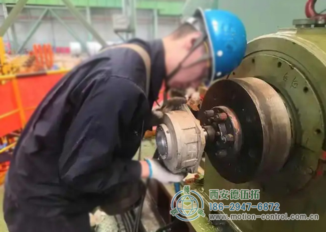 图为工人为彩涂酸轧轧机回装编码器的照片